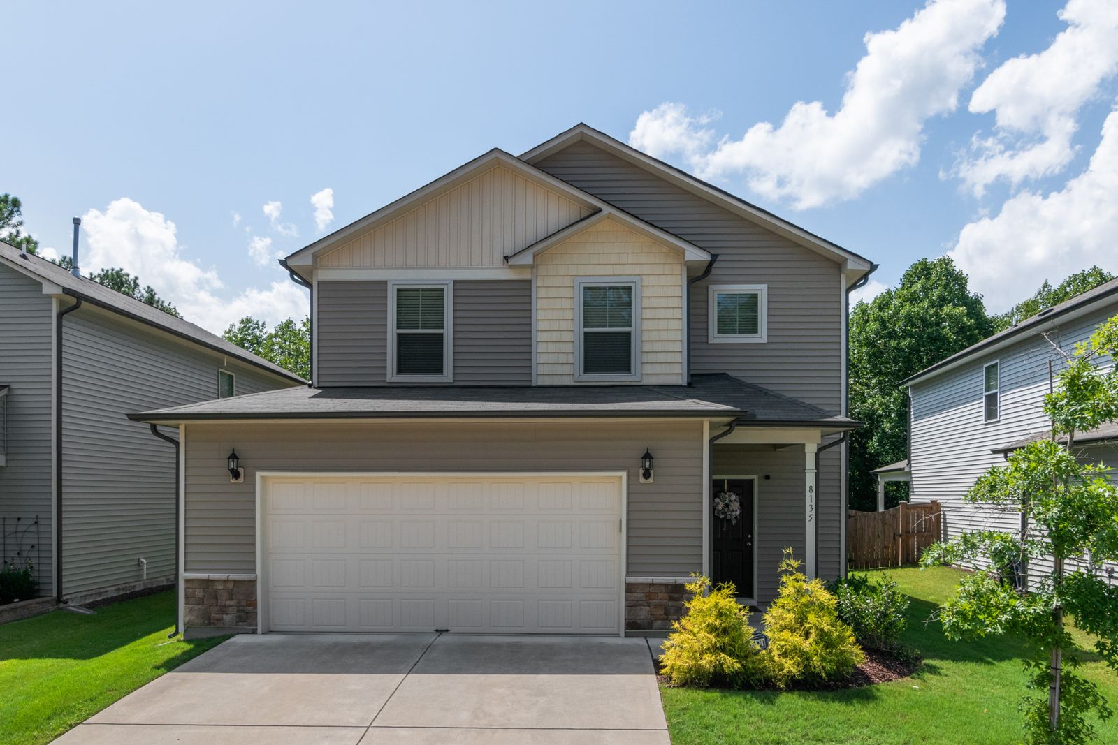 Finished suburban home with gray horizontal siding, light gable accents, white window trim and dark gutters along the roof edges.