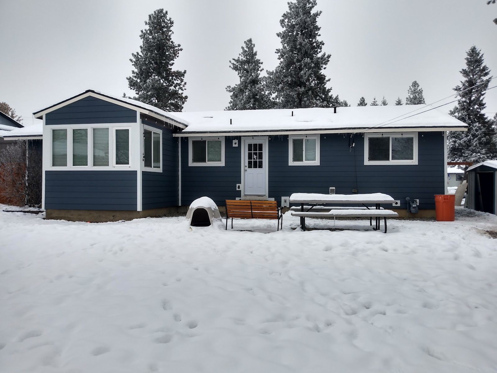 Blue horizontal siding and white trim on a Signature project, with a bay-window projection and snow in the yard.